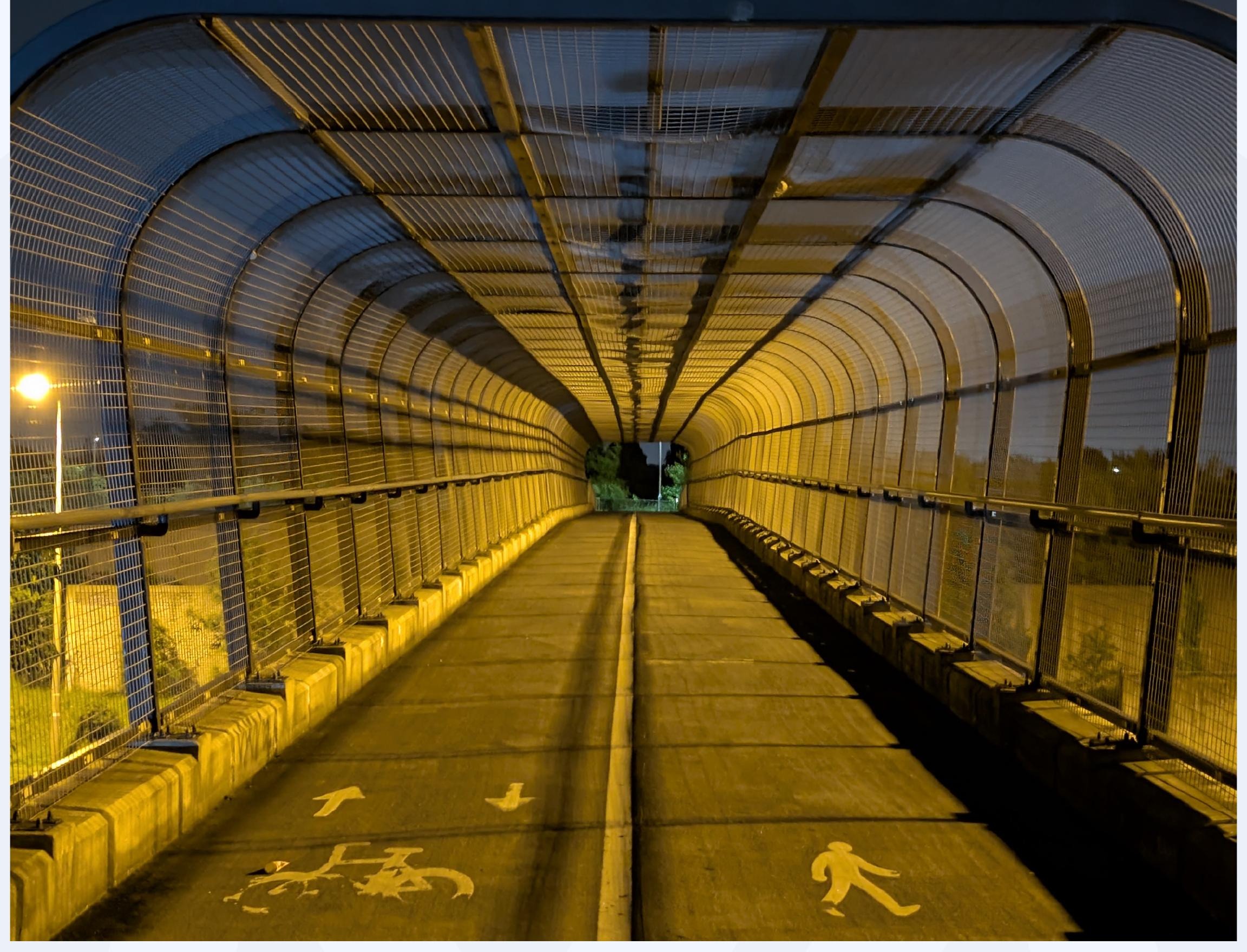Yellow-lit covered pedestrian crosswalk tunnel