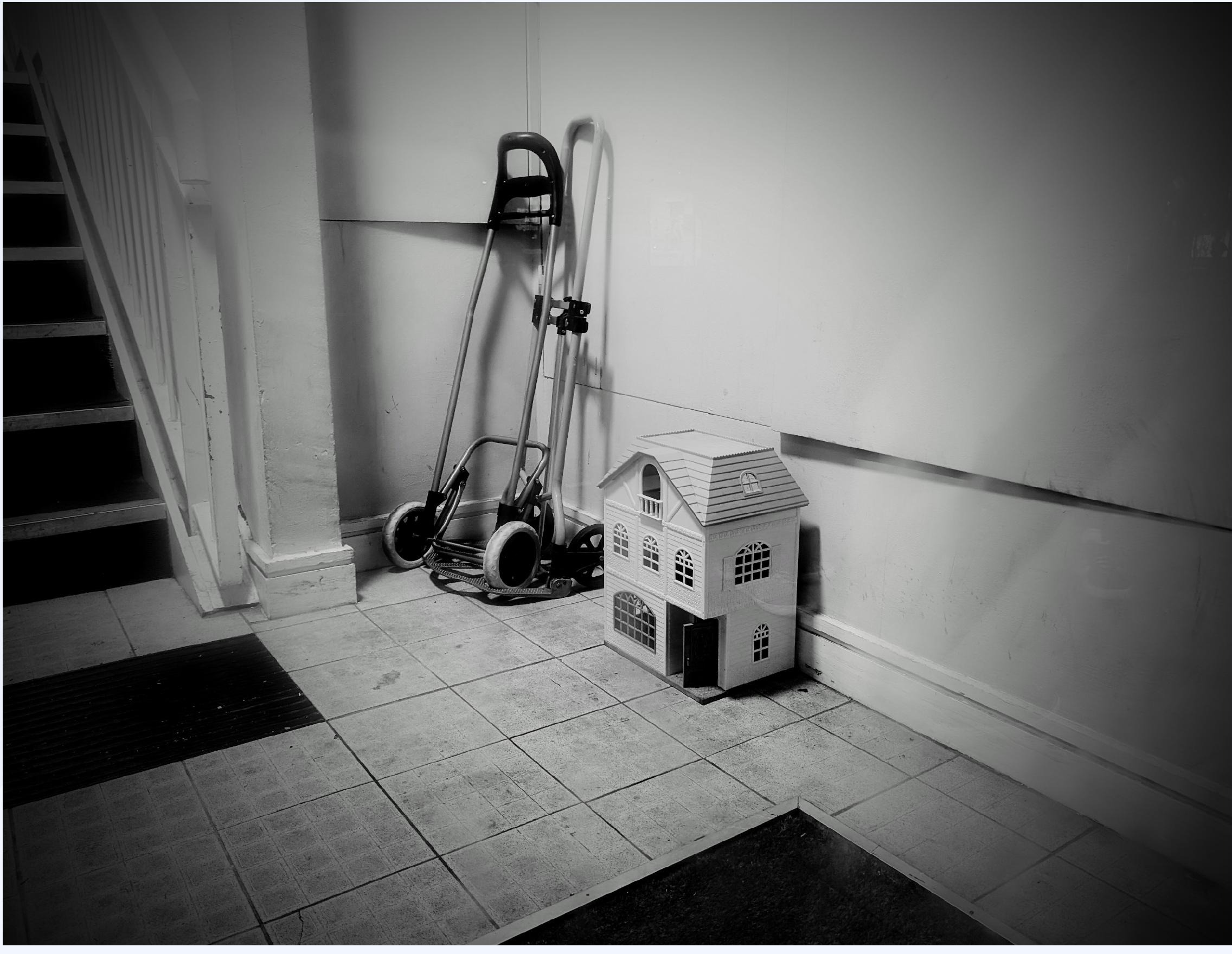 Black and white photo of a hallway with a dollhouse