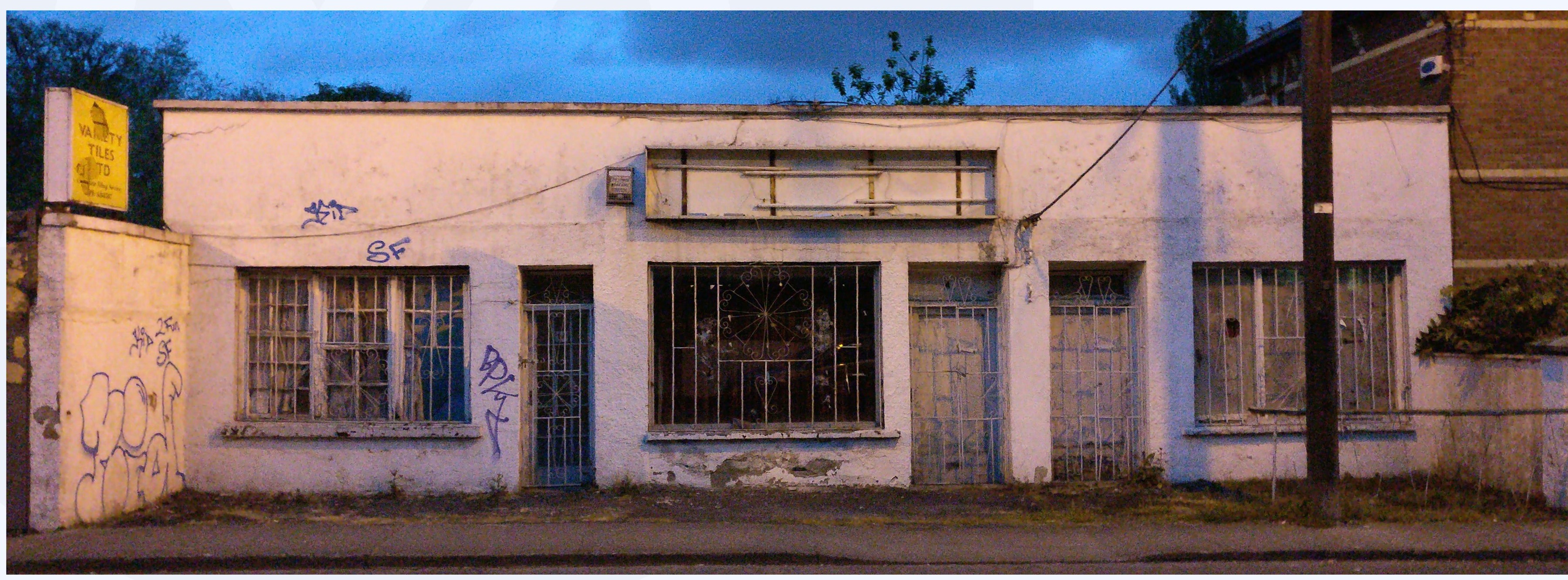Abandoned whitewashed shopfront at dusk