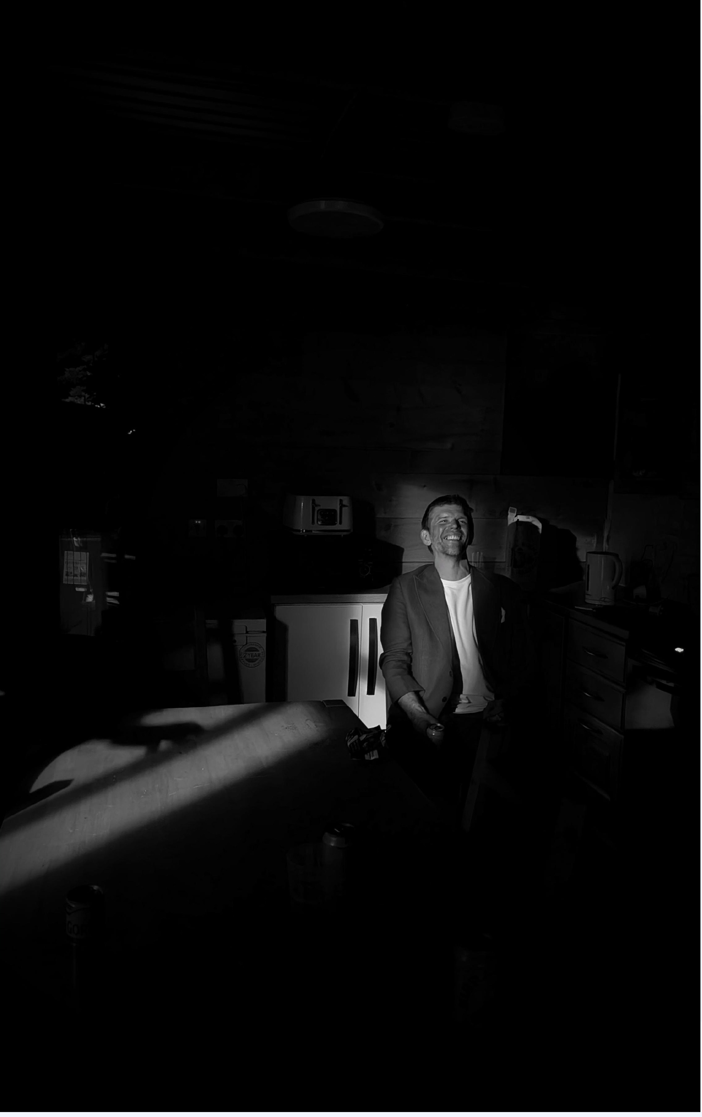 Moody black and white photo of a man laughing in a kitchen